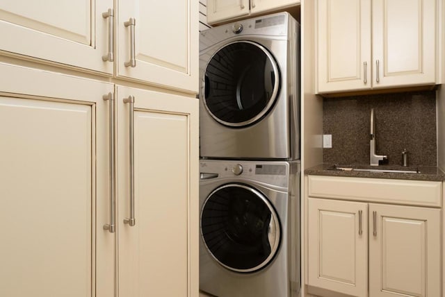 washroom with cabinets, stacked washing maching and dryer, and sink