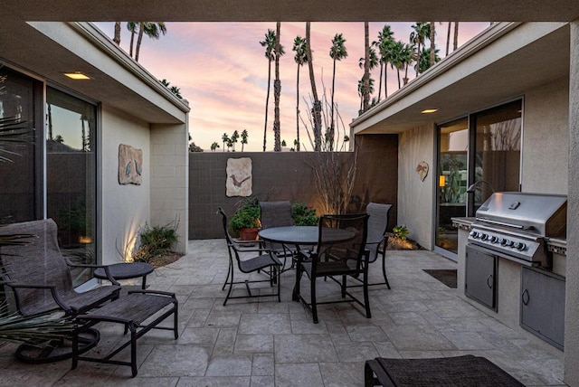 patio terrace at dusk with an outdoor kitchen and grilling area