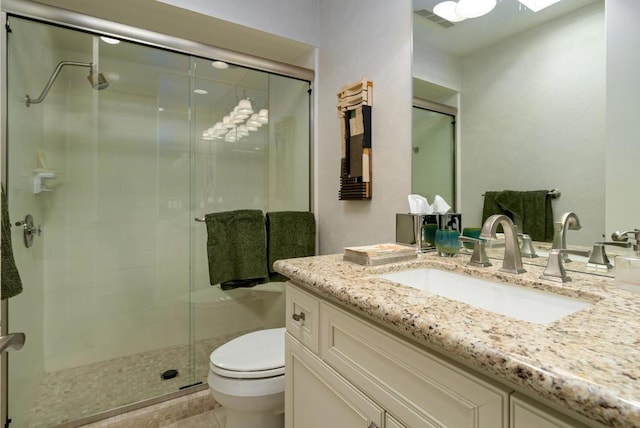 bathroom with vanity, a shower with door, and toilet