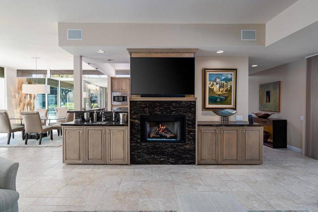 kitchen featuring dark stone countertops, decorative light fixtures, a fireplace, and stainless steel appliances