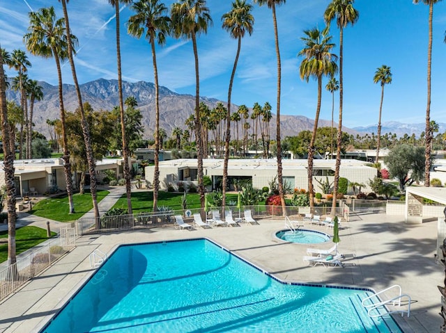 view of swimming pool featuring a community hot tub, a mountain view, and a patio