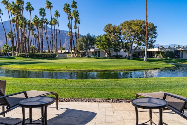 view of property's community featuring a yard, a patio, and a water and mountain view