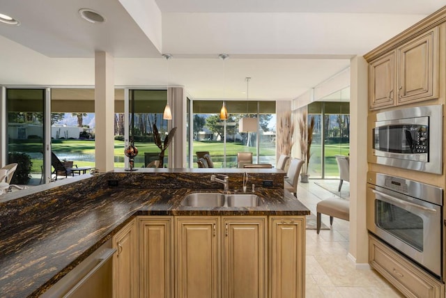 kitchen featuring sink, hanging light fixtures, stainless steel appliances, kitchen peninsula, and dark stone counters