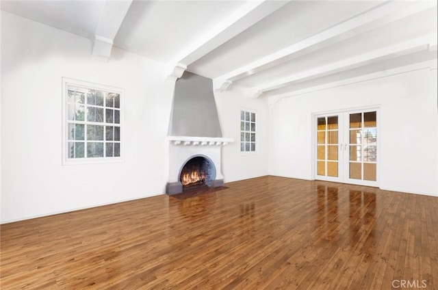 unfurnished living room featuring beamed ceiling, a fireplace, french doors, and hardwood / wood-style flooring