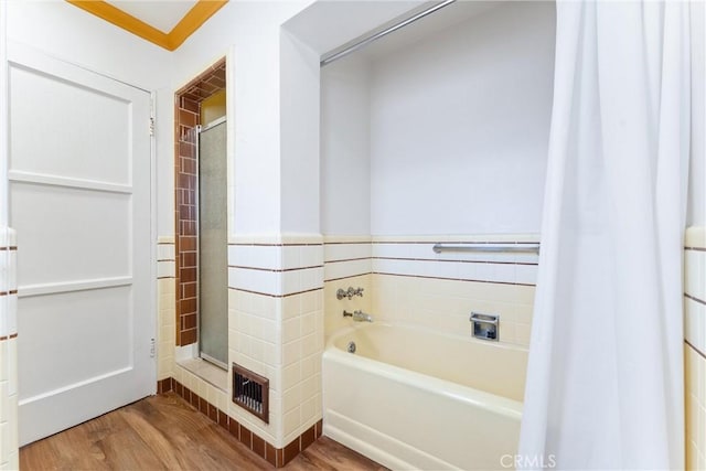 bathroom with hardwood / wood-style floors, tile walls, and a tub