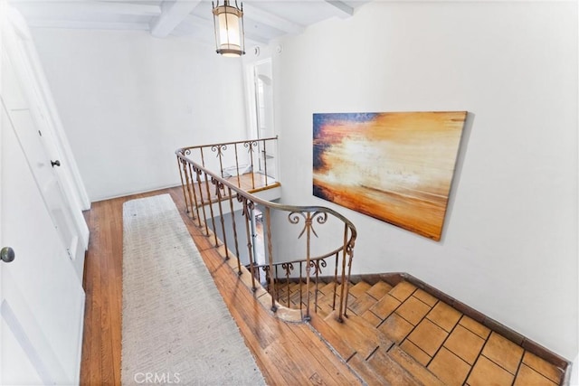 stairway with beamed ceiling and hardwood / wood-style floors