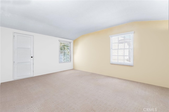 carpeted empty room with vaulted ceiling