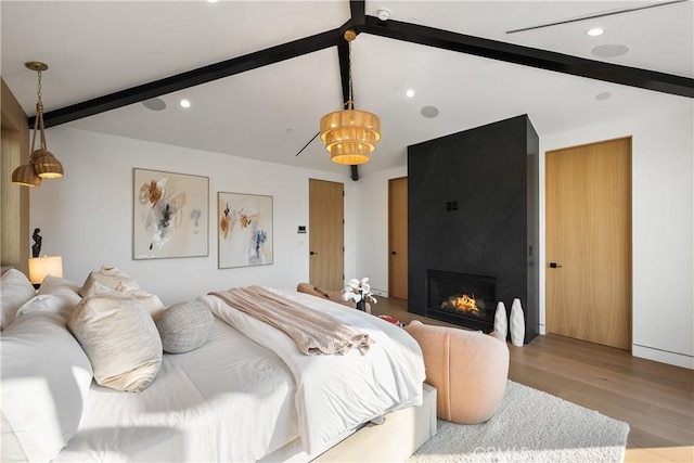 bedroom featuring vaulted ceiling with beams, a large fireplace, and light wood-type flooring