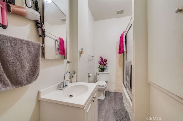 full bathroom with vanity, combined bath / shower with glass door, wood-type flooring, and toilet