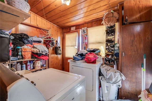 clothes washing area with wood ceiling, washer and clothes dryer, and wood walls