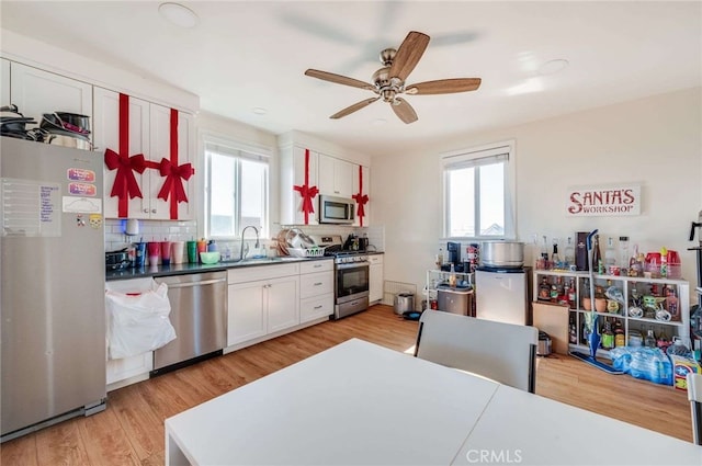 kitchen featuring sink, white cabinetry, light hardwood / wood-style flooring, stainless steel appliances, and backsplash