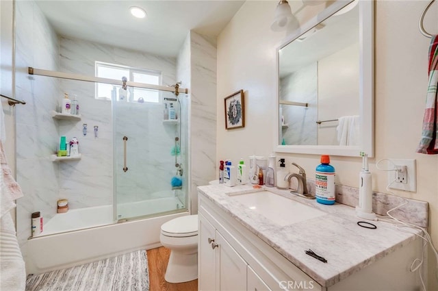 full bathroom featuring toilet, vanity, shower / bath combination with glass door, and hardwood / wood-style flooring