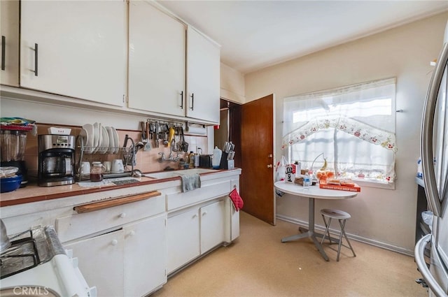 kitchen with white cabinetry and stainless steel fridge