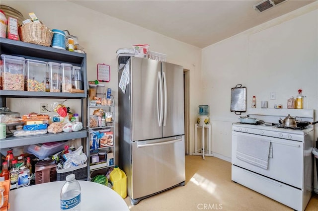 kitchen featuring light carpet, stainless steel fridge, and white gas stove