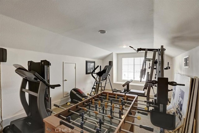 exercise room with vaulted ceiling and a textured ceiling