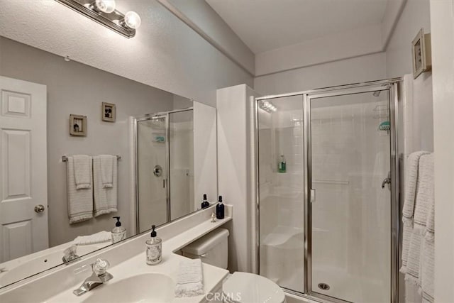 bathroom featuring toilet, vanity, and a shower with shower door