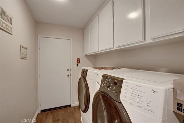 clothes washing area with cabinets, wood-type flooring, and washer and dryer