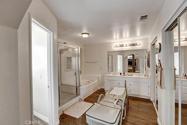 bathroom featuring vanity, hardwood / wood-style flooring, and plus walk in shower