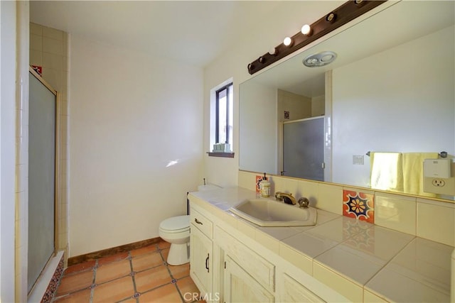 bathroom with a shower with door, vanity, tile patterned flooring, and toilet