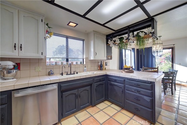 kitchen featuring sink, white cabinetry, stainless steel dishwasher, tile counters, and kitchen peninsula