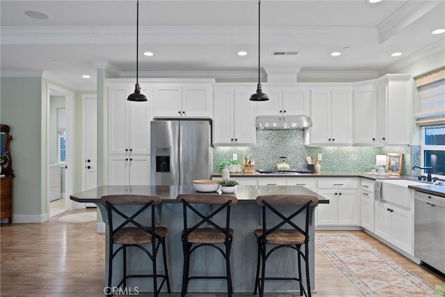 kitchen with stainless steel appliances, decorative light fixtures, sink, and a kitchen island