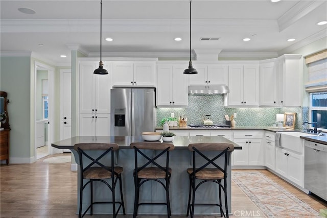 kitchen with a kitchen island, sink, stainless steel appliances, and pendant lighting