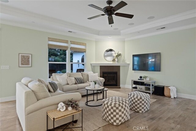 living room with ornamental molding, ceiling fan, and light wood-type flooring