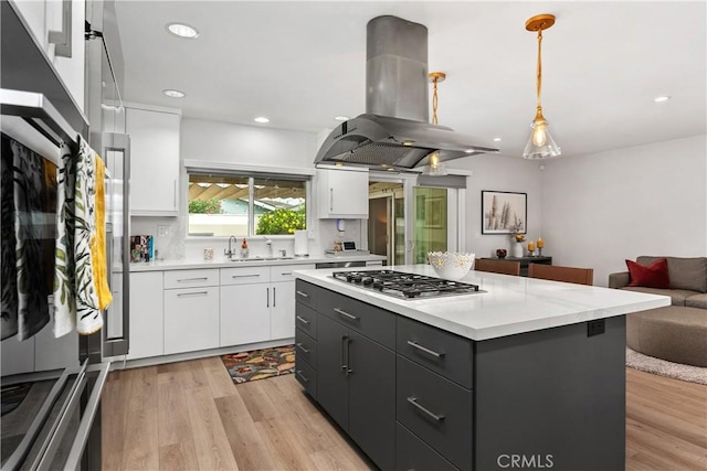 kitchen with island range hood, decorative light fixtures, and white cabinets