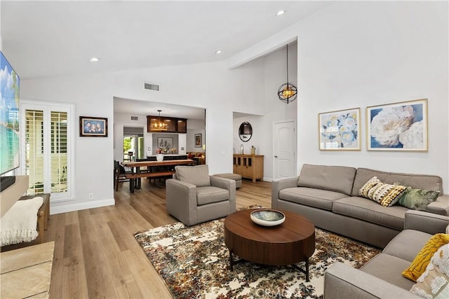 living room featuring high vaulted ceiling and light hardwood / wood-style floors