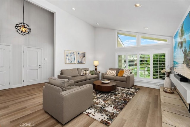 living room featuring high vaulted ceiling and light hardwood / wood-style floors