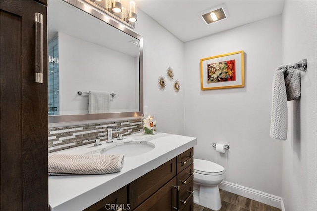 bathroom with tasteful backsplash, vanity, wood-type flooring, and toilet