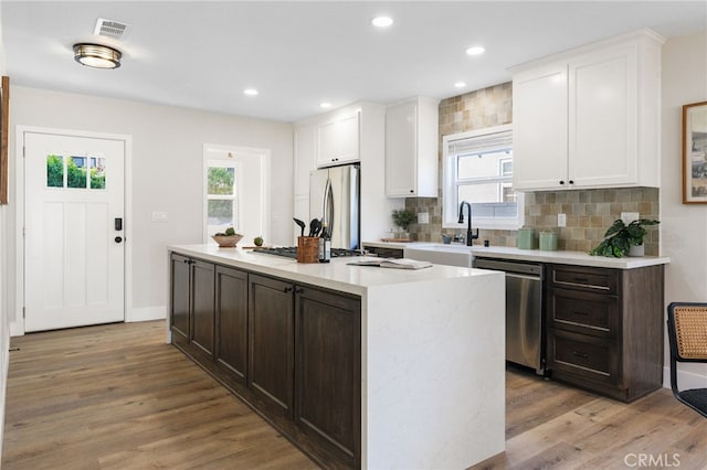 kitchen featuring a kitchen island, white cabinetry, appliances with stainless steel finishes, and light hardwood / wood-style floors