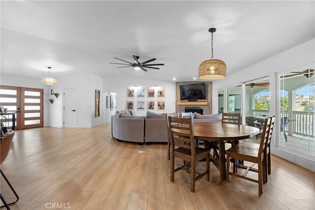 dining room with a fireplace, light hardwood / wood-style flooring, and ceiling fan