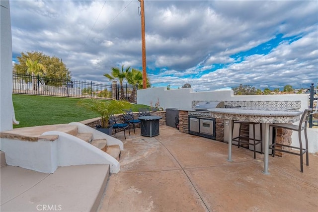 view of patio / terrace featuring a bar, a grill, and an outdoor kitchen