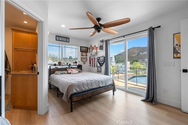 bedroom featuring multiple windows, a mountain view, access to outside, and light hardwood / wood-style floors