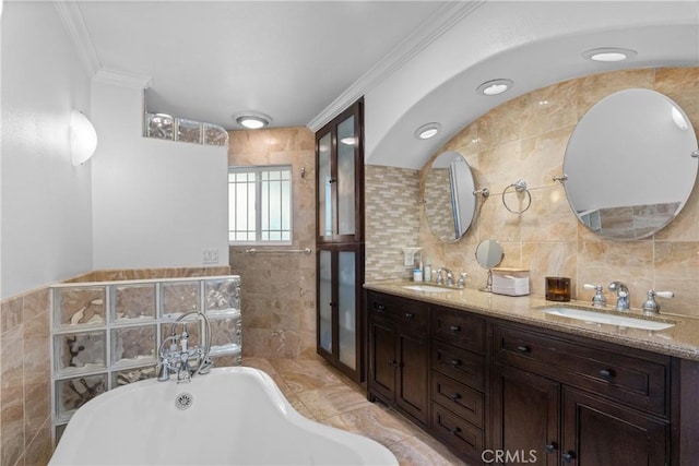 bathroom with ornamental molding, a tub, tile walls, and vanity