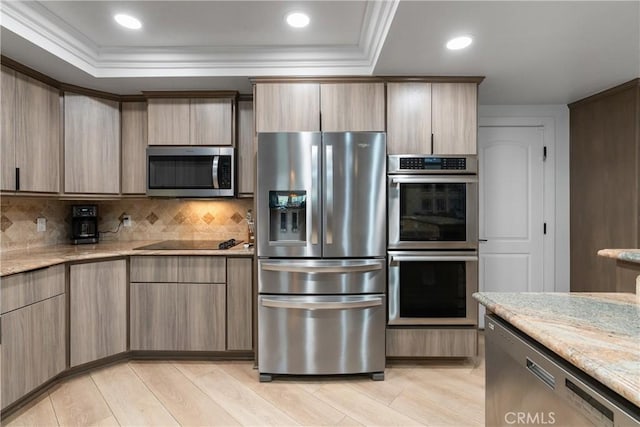 kitchen featuring crown molding, stainless steel appliances, light stone countertops, light hardwood / wood-style floors, and backsplash