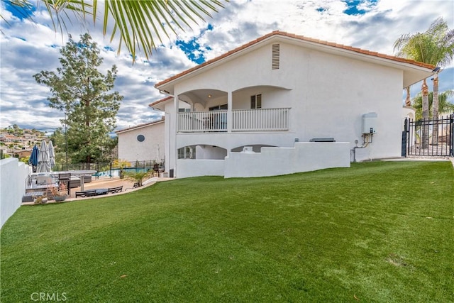 rear view of property with a balcony and a lawn