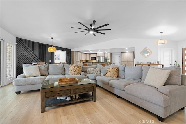 living room featuring ceiling fan, lofted ceiling, and light hardwood / wood-style flooring