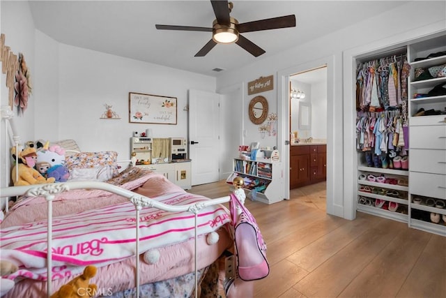 bedroom featuring ceiling fan, ensuite bath, a closet, and light wood-type flooring