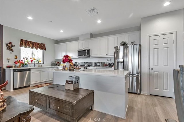 kitchen featuring stainless steel appliances, white cabinetry, a center island, and light hardwood / wood-style floors