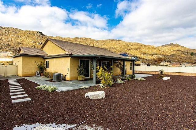 rear view of house with central AC unit, a mountain view, and a patio