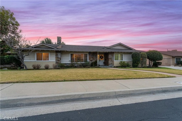 ranch-style house featuring a garage and a yard