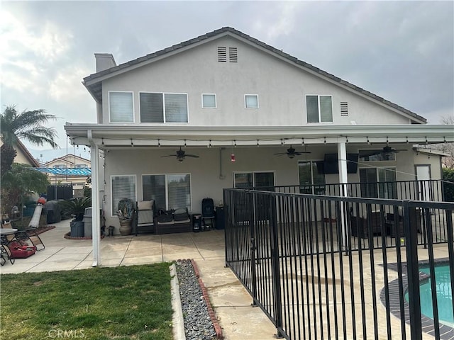 rear view of house featuring ceiling fan, a fenced in pool, and a patio