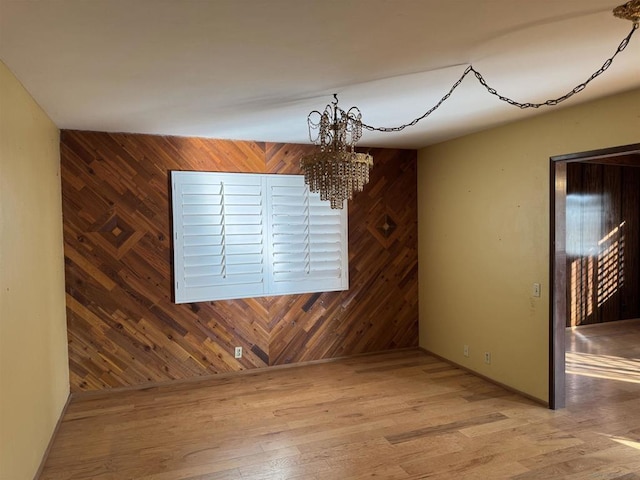 unfurnished dining area with hardwood / wood-style flooring, wooden walls, and a chandelier