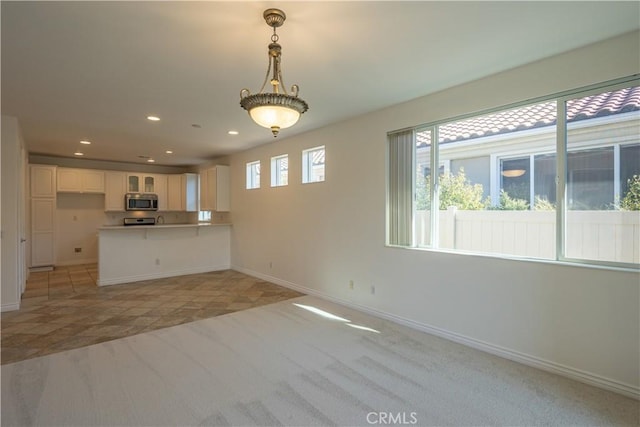 kitchen featuring white cabinetry, light colored carpet, decorative light fixtures, and kitchen peninsula