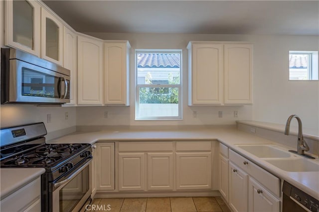 kitchen with white cabinetry, appliances with stainless steel finishes, sink, and light tile patterned floors