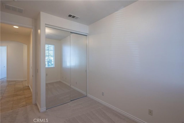 unfurnished bedroom with light colored carpet and a closet