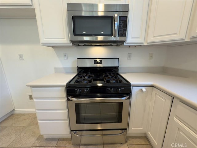 kitchen with light tile patterned floors, stainless steel appliances, and white cabinets