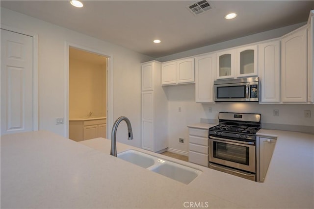 kitchen with stainless steel appliances, white cabinetry, and sink